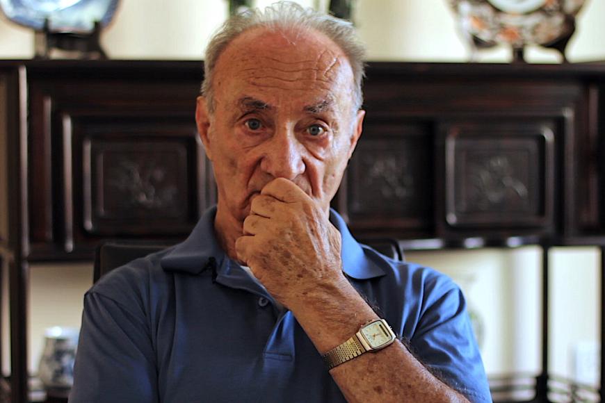 An old man is looking thoughtfully into the camera