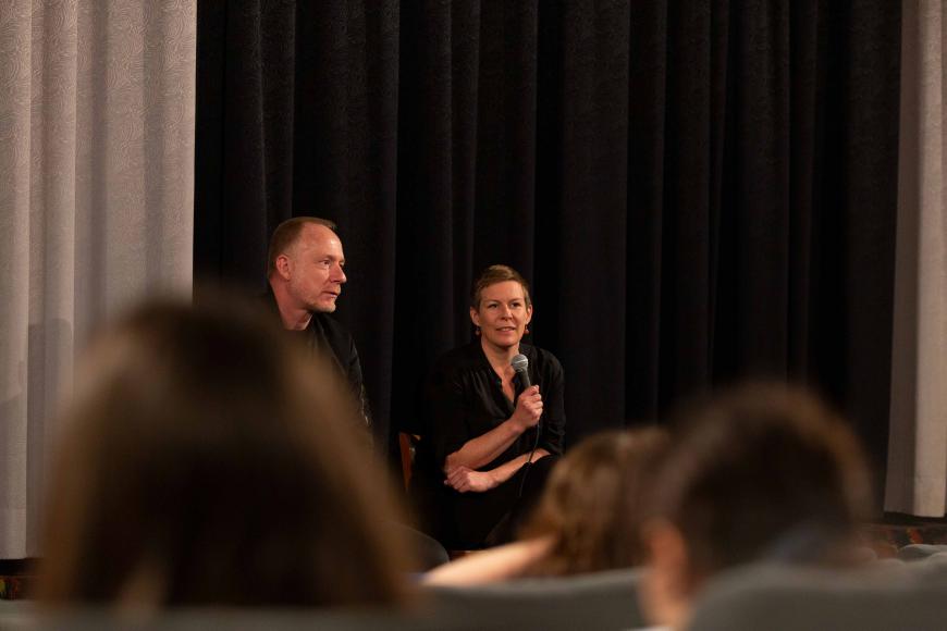 Luc-Carolin Ziemann (Leiterin von DOK Bildung) in einem Filmgespräch mit Regisseur Carsten Rau . Sie sitzen in einem Kino vor der Leinwand und blicken Richtung Publikum.