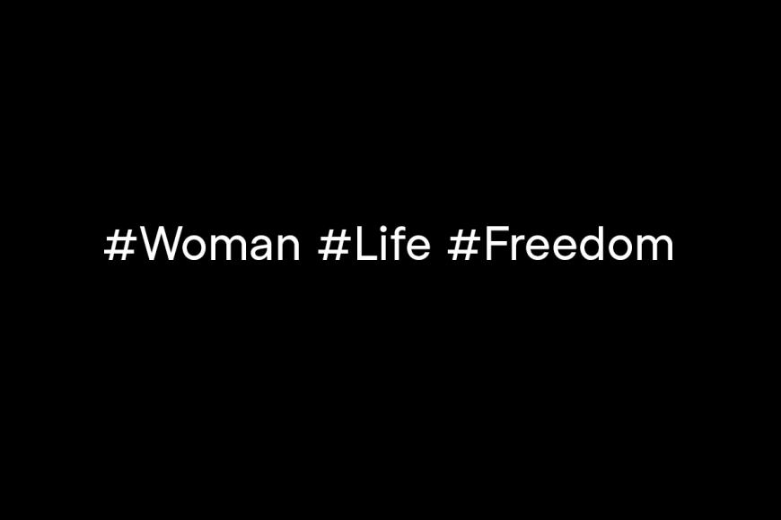 Eine Texttafel mit weißer Schrift auf schwarz: "#Woman #Life #Freedom".