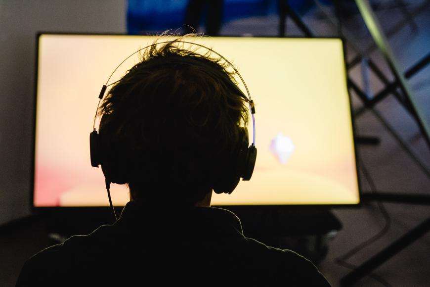 A person with headphones on looks at a brightly lit screen.