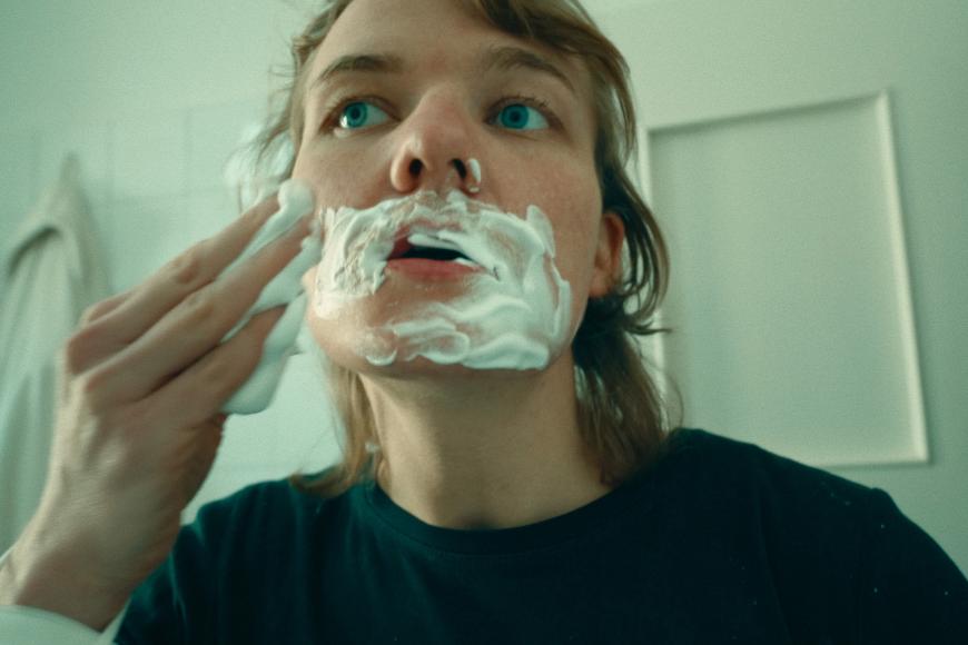 Eine Frau seift sich im Gesicht mit Rasierschaum ein.