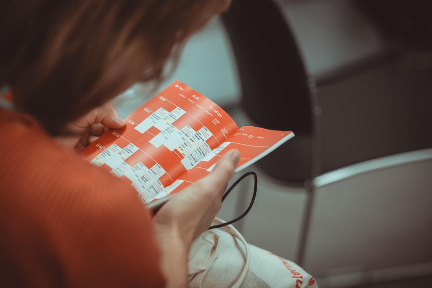 Eine Person blättert im Programmheft von DOK Leipzig.