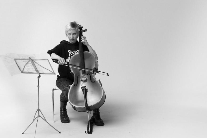 Eine junge Frau in einem Kapuzenpullover spielt Cello.