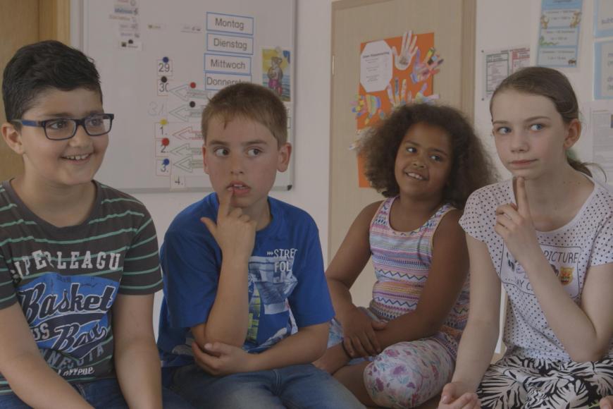 Vier Kinder sitzen zusammen in einem Klassenraum.