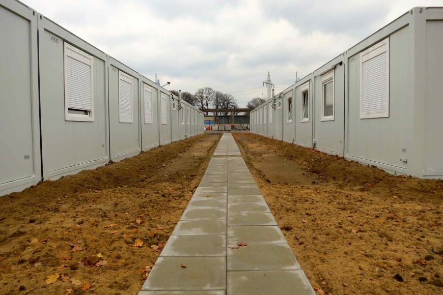 Ein Weg aus Pflastersteinen zwischen zwei Reihen aus Wohncontainern.