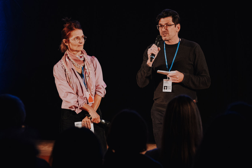 A man and a woman on stage pitching their documentary project.