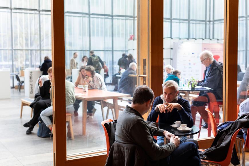 Im Festivalzentrum sitzen viele Menschen in kleinen Grüppchen und plaudern